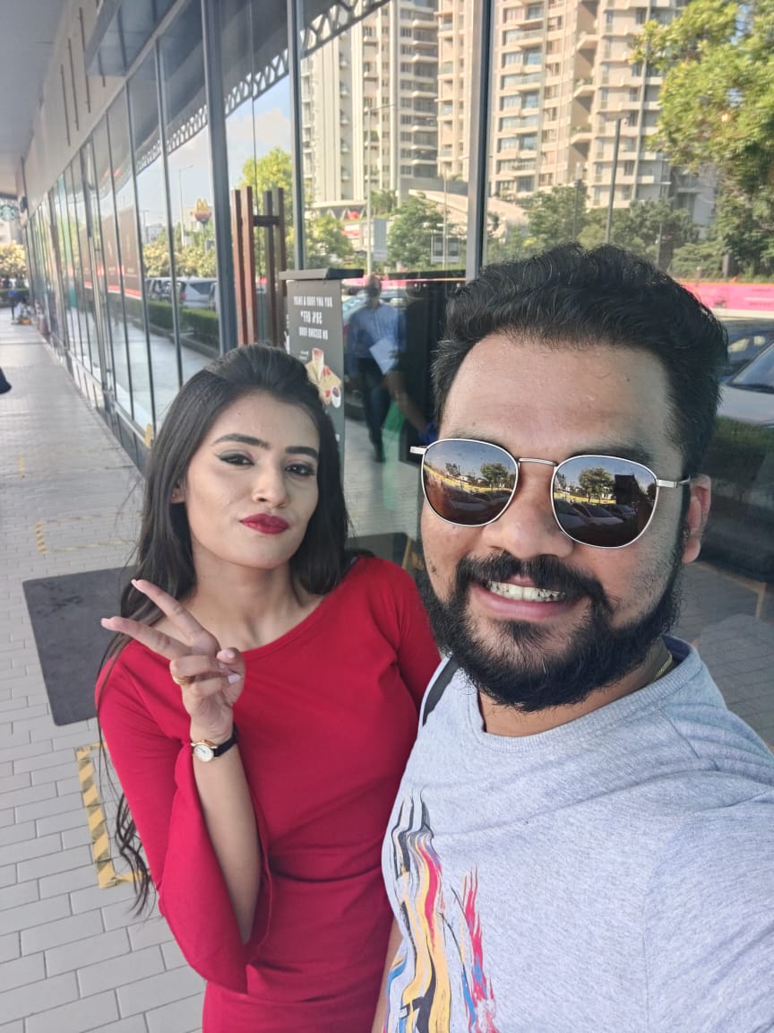 Outdoor selfie with a companion in a city walkway surrounded by tall buildings