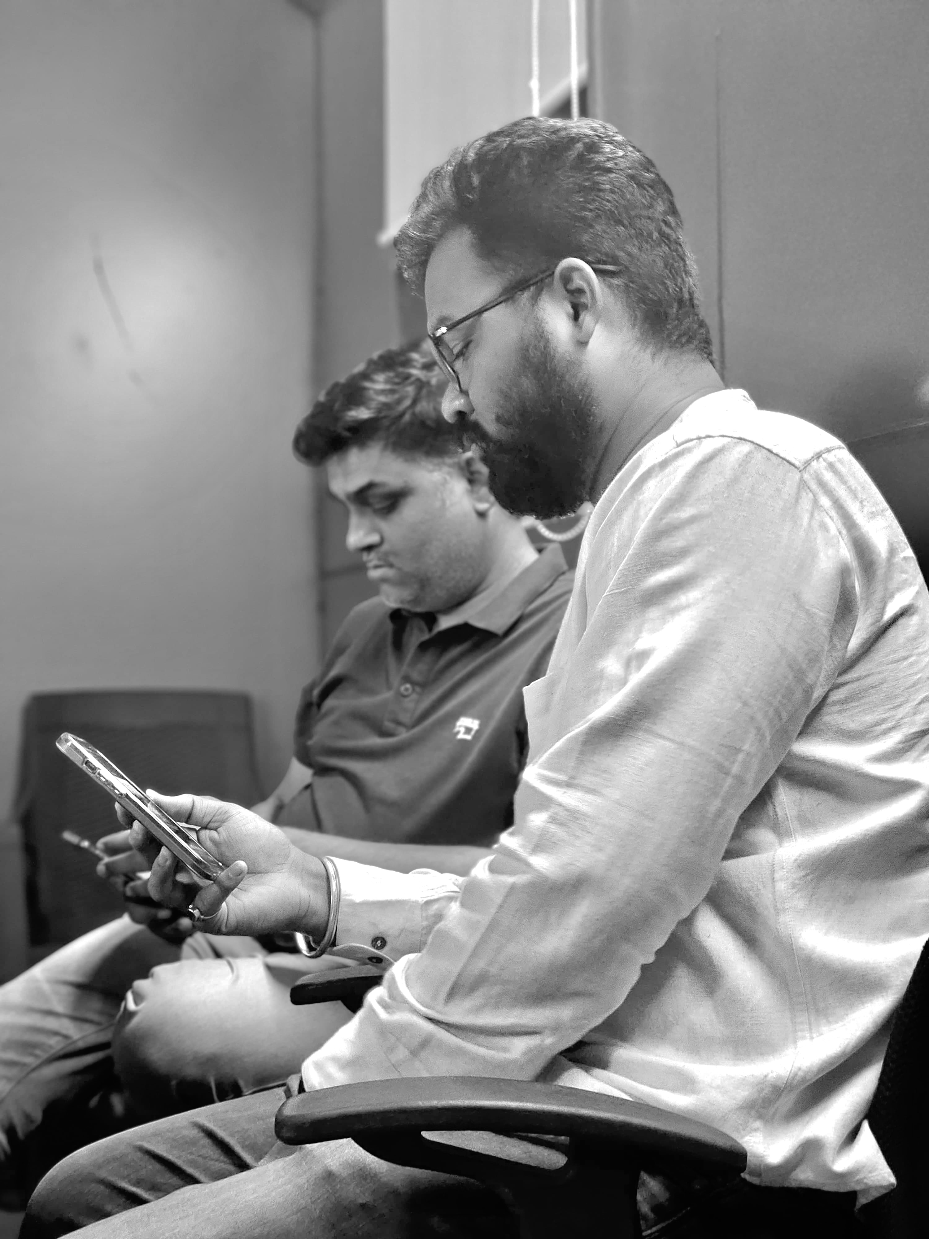 Black and white candid photo of two people seated and looking at a phone