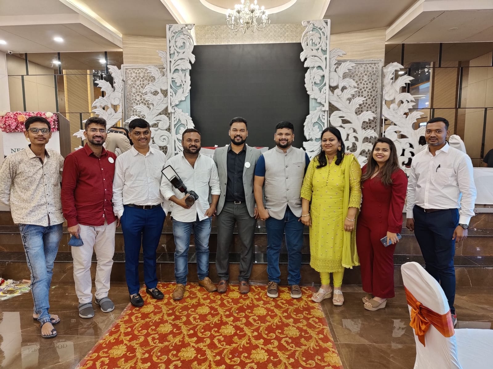Group photo at a decorated event venue with a stage backdrop